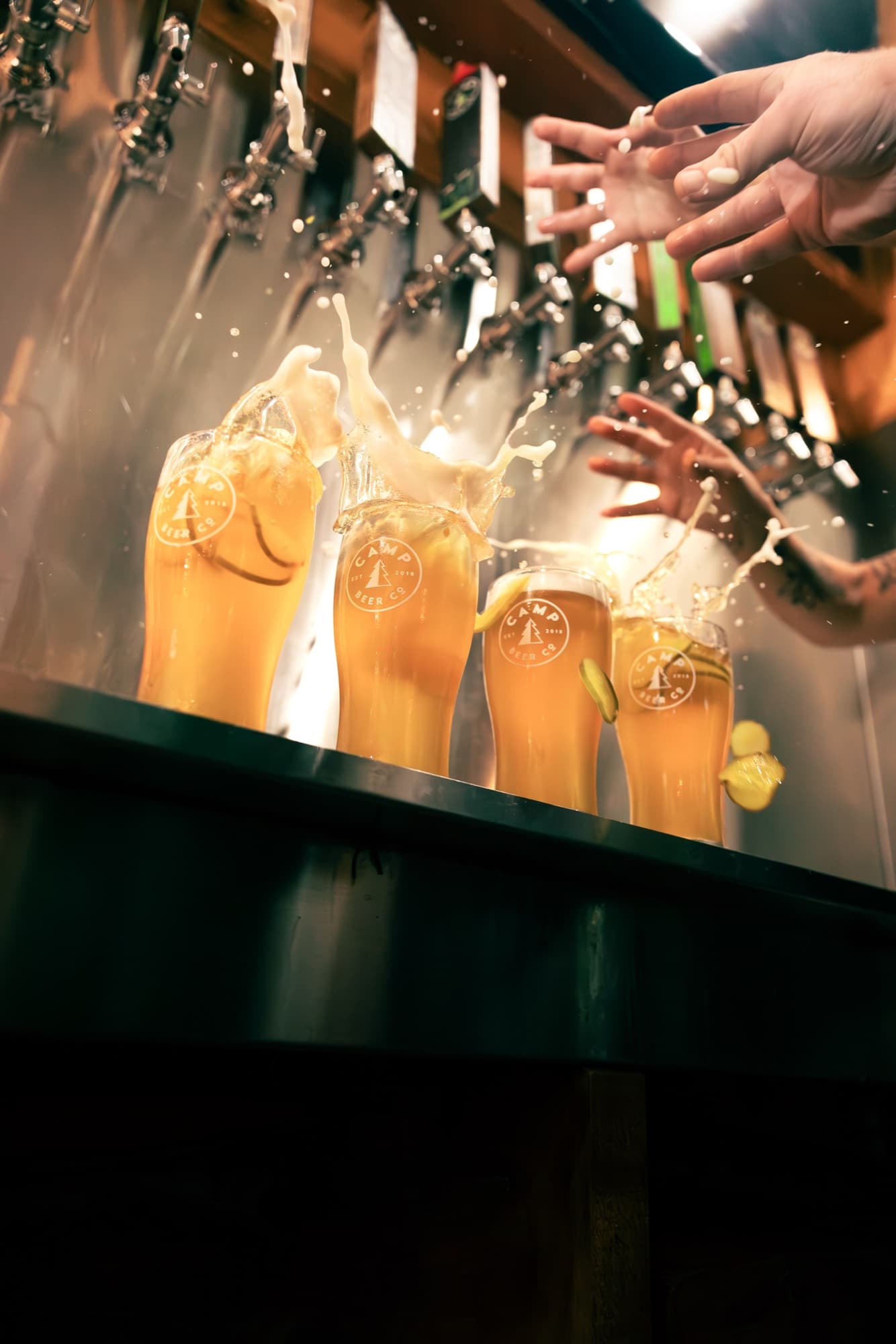 Camp Beer Co. glasses mid-splash under the taps